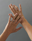 Milgrain Fairmined gold wedding band with Canadian diamonds shown on crossed women's hands.