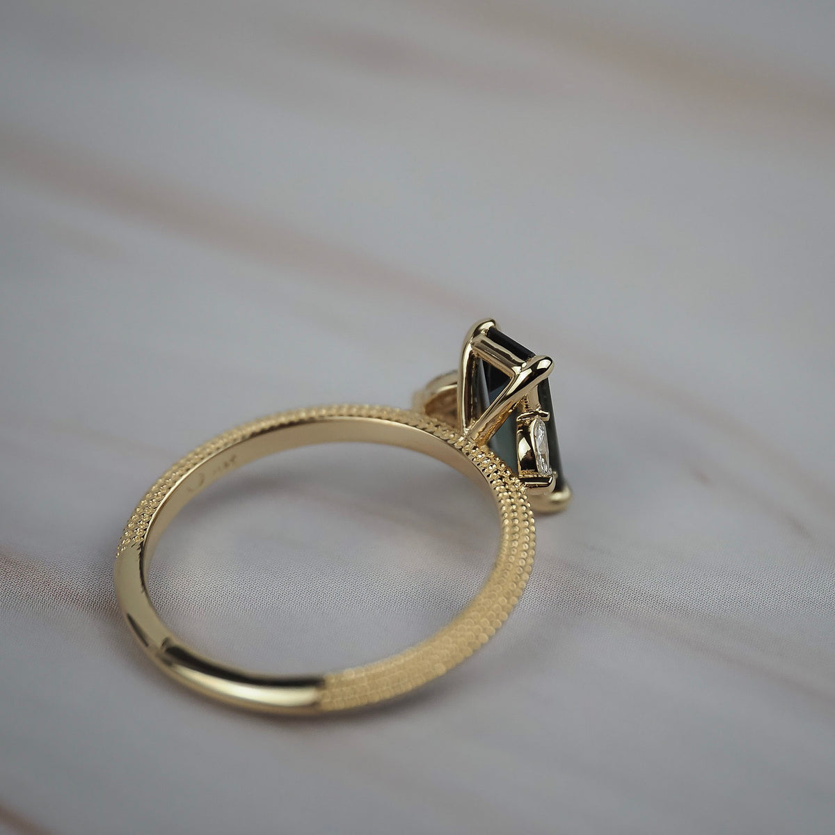 Close-up of the back of the Millie cluster solitaire showing the setting, side profile, and milgrained beaded gold band. 