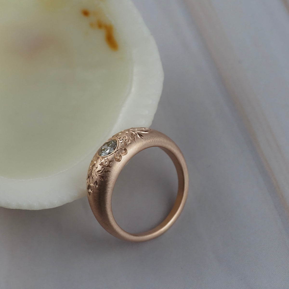 Close-up of the hand engraved floral details on the side of the Mrs. Erykah Fairmined gold engagement ring.