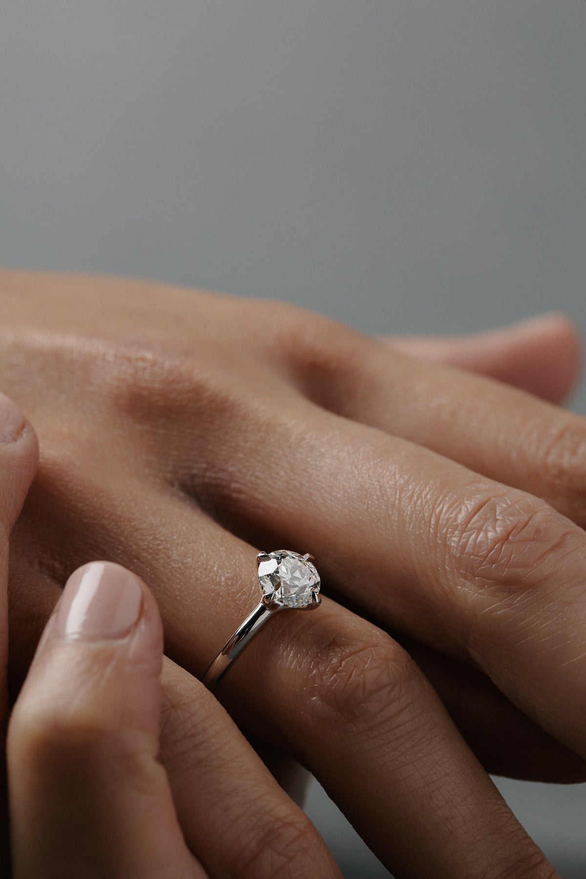Close-up of a woman wearing the Myra compass platinum claw solitaire engagement ring with an old European cut diamond.