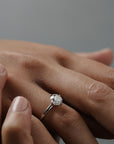 Close-up of a woman wearing the Myra compass platinum claw solitaire engagement ring with an old European cut diamond.