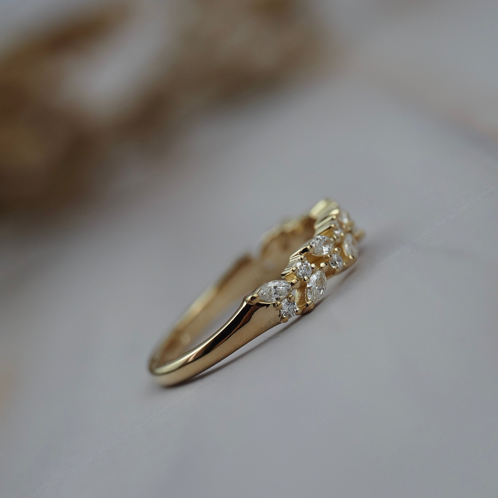 Side close-up of the Navette diamond cluster wedding band showing round and marquise diamonds in a gold setting.
