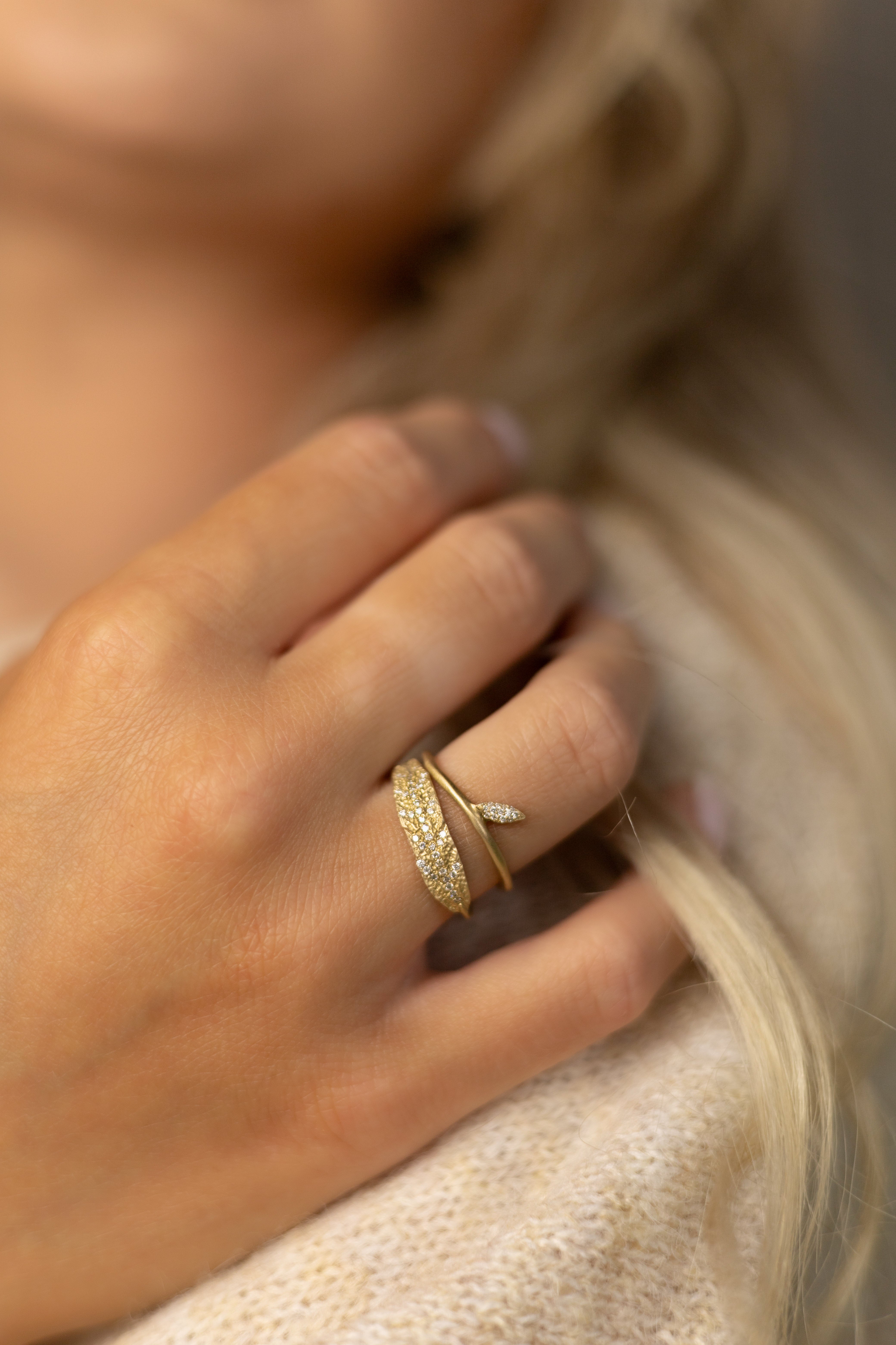 Stylized close-up of a model'd hand wearing organic pave diamond leaf rings.
