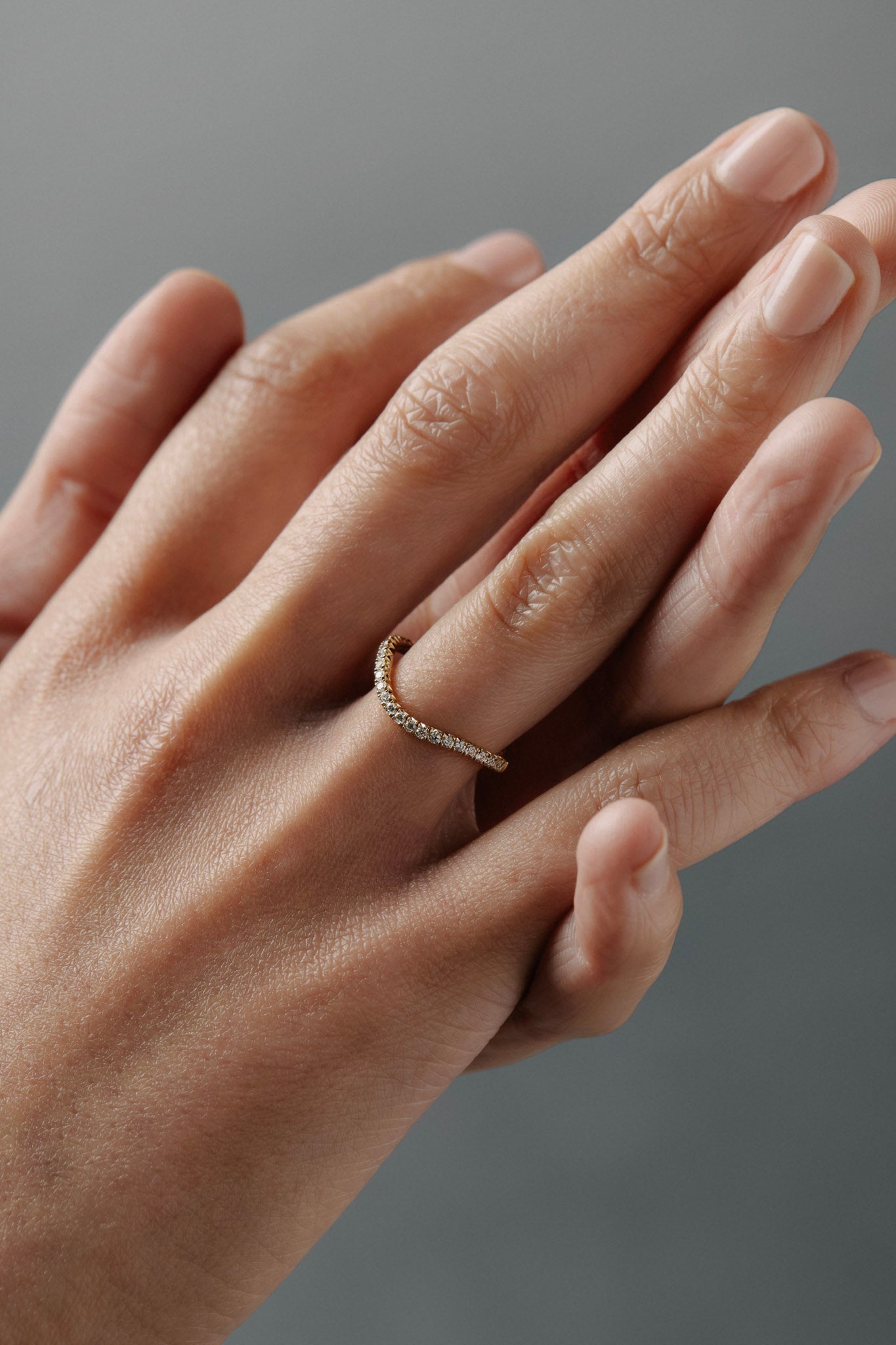 Close-up of wearing the Pernelle curved French pave diamond wedding band on her hand.