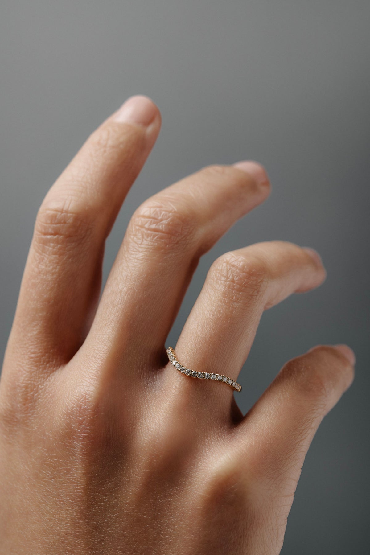 Close-up of the Pernelle curved French pave diamond wedding band worn on a woman's finger.