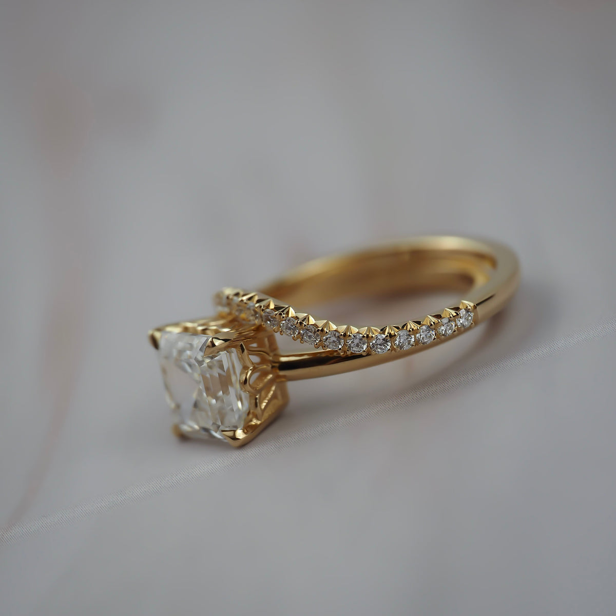 Close-up of the Pernell curved French pave diamond weeding band paired with an asscher cut solitaire engagement ring. 