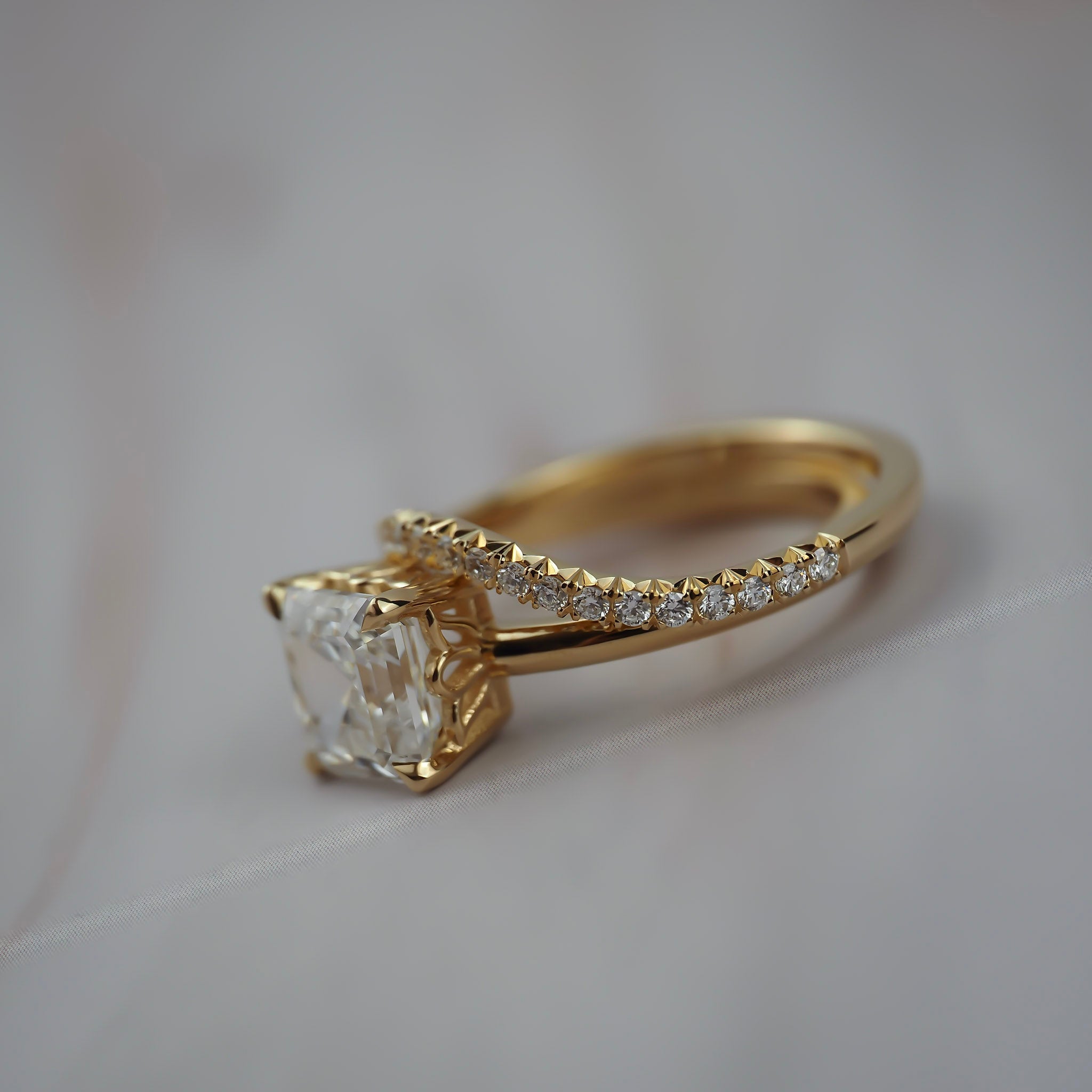 Close-up of the Pernell curved French pave diamond weeding band paired with an asscher cut solitaire engagement ring. 