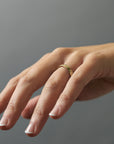 Close-up of hand engraved poppy  flowers on a Fairmined yellow gold band worn on women's hand.