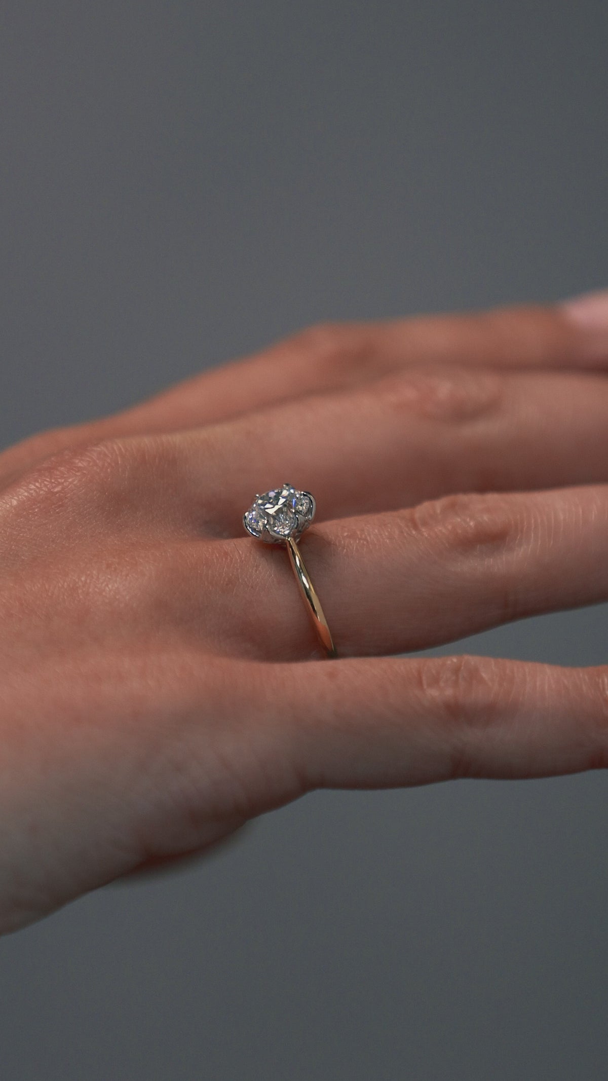 Close-up video of a woman wearing the Cala tulip-styles solitaire, featuring a two tone platinum and gold setting with a round Old European cut diamond. 