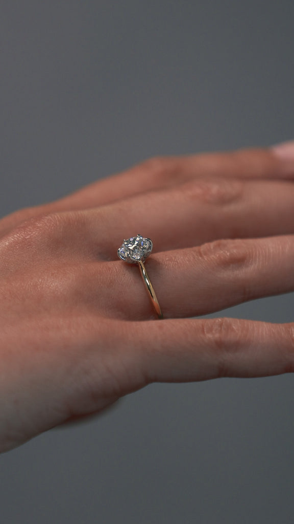 Close-up video of a woman wearing the Cala tulip-styles solitaire, featuring a two tone platinum and gold setting with a round Old European cut diamond. 