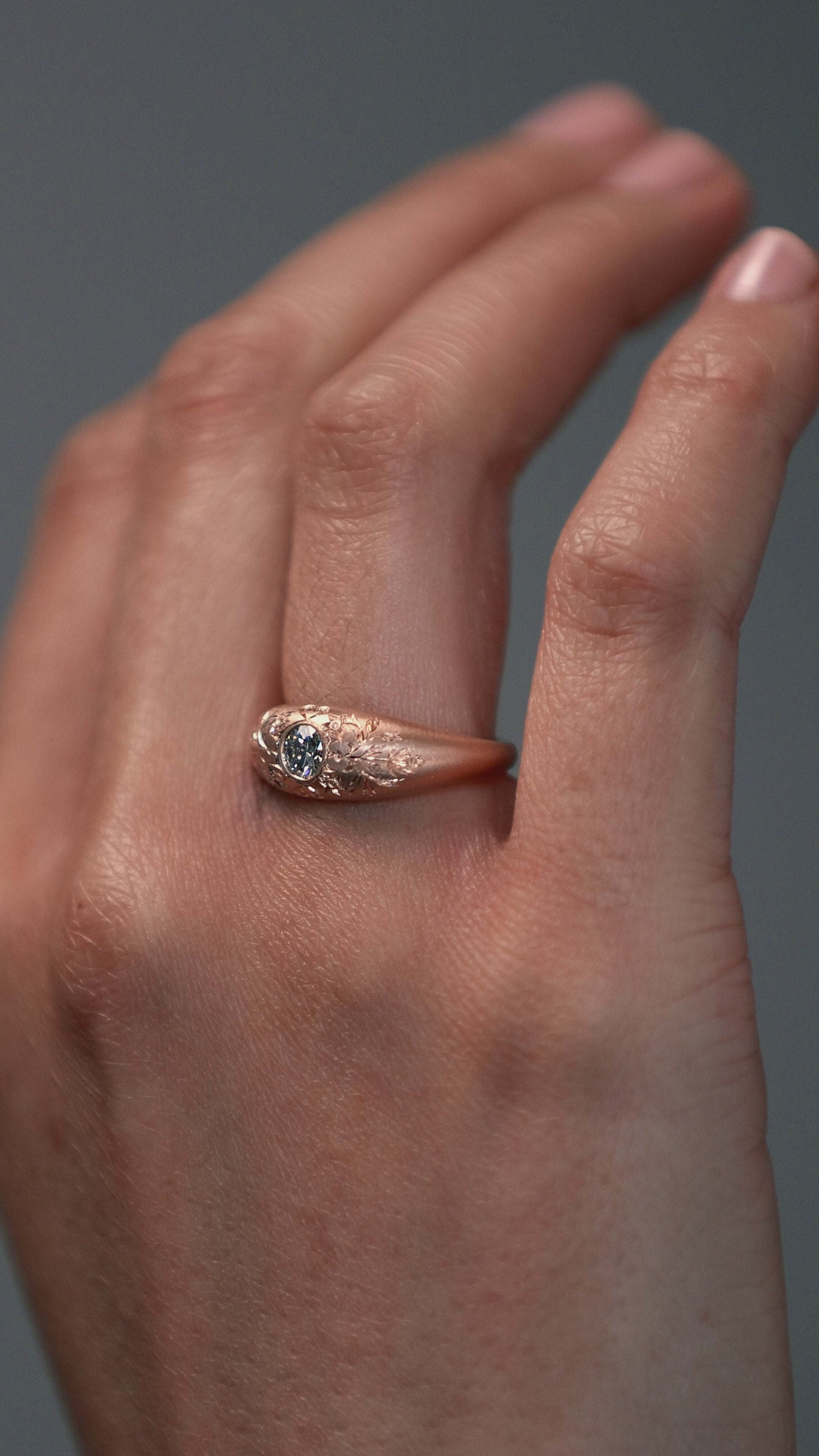 Close-up video of the Mrs. Erykah hand engraved floral bombe engagement ring in Fairmined gold with a Canadian diamond horns on a woman's hand.