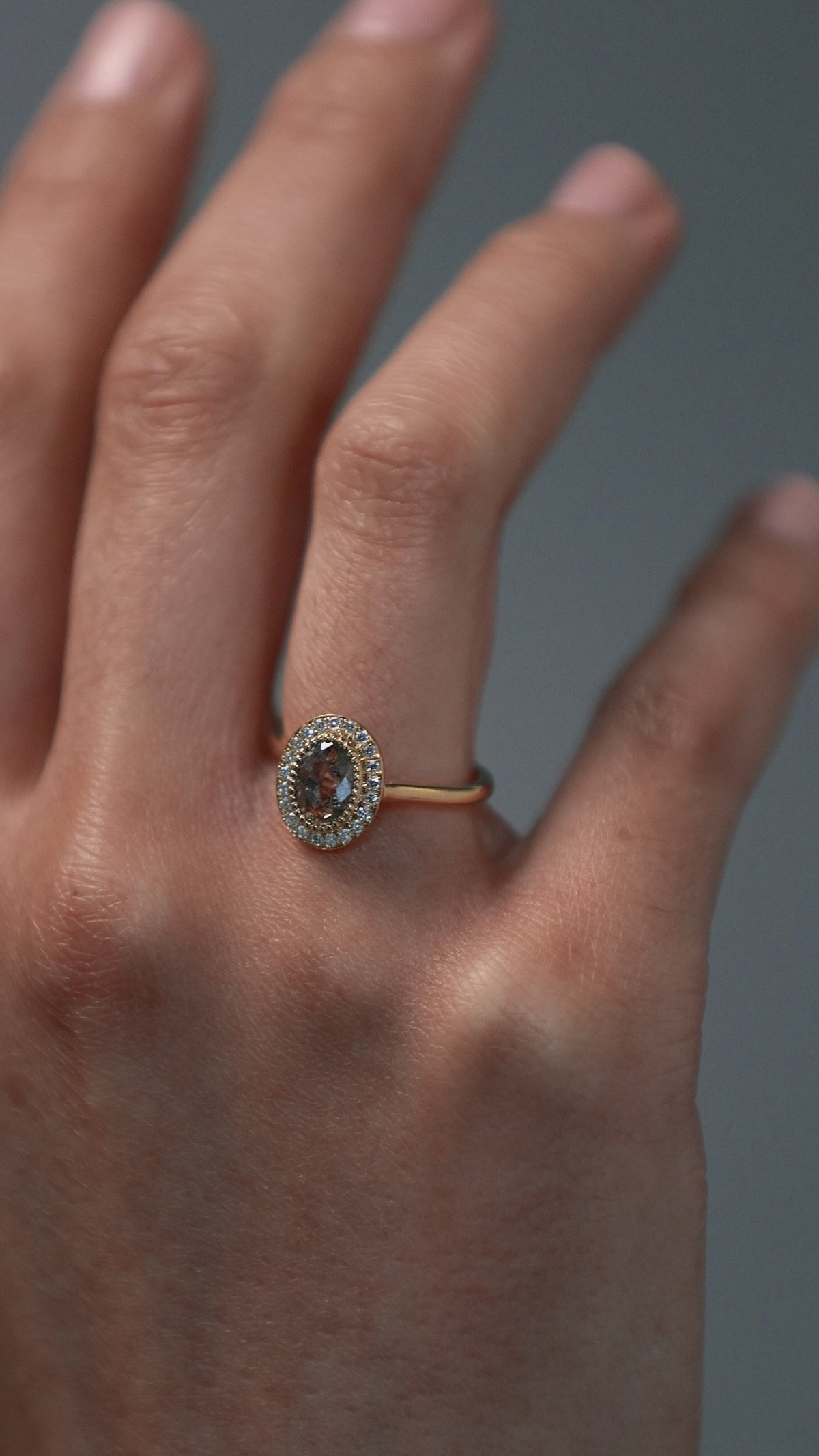 Close-up video of woman wearing the Air halo solitaire with a champagne toned Australian salt and pepper rose cut diamond surrounded by round Canadian diamonds. 