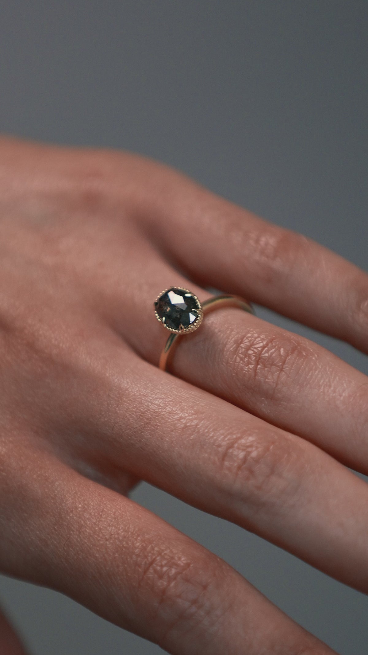 Close-up video of a woman wearing the Elanor salt and pepper oval diamond six-claw solitaire, showing the Art Deco woven setting and milgrain edge. 