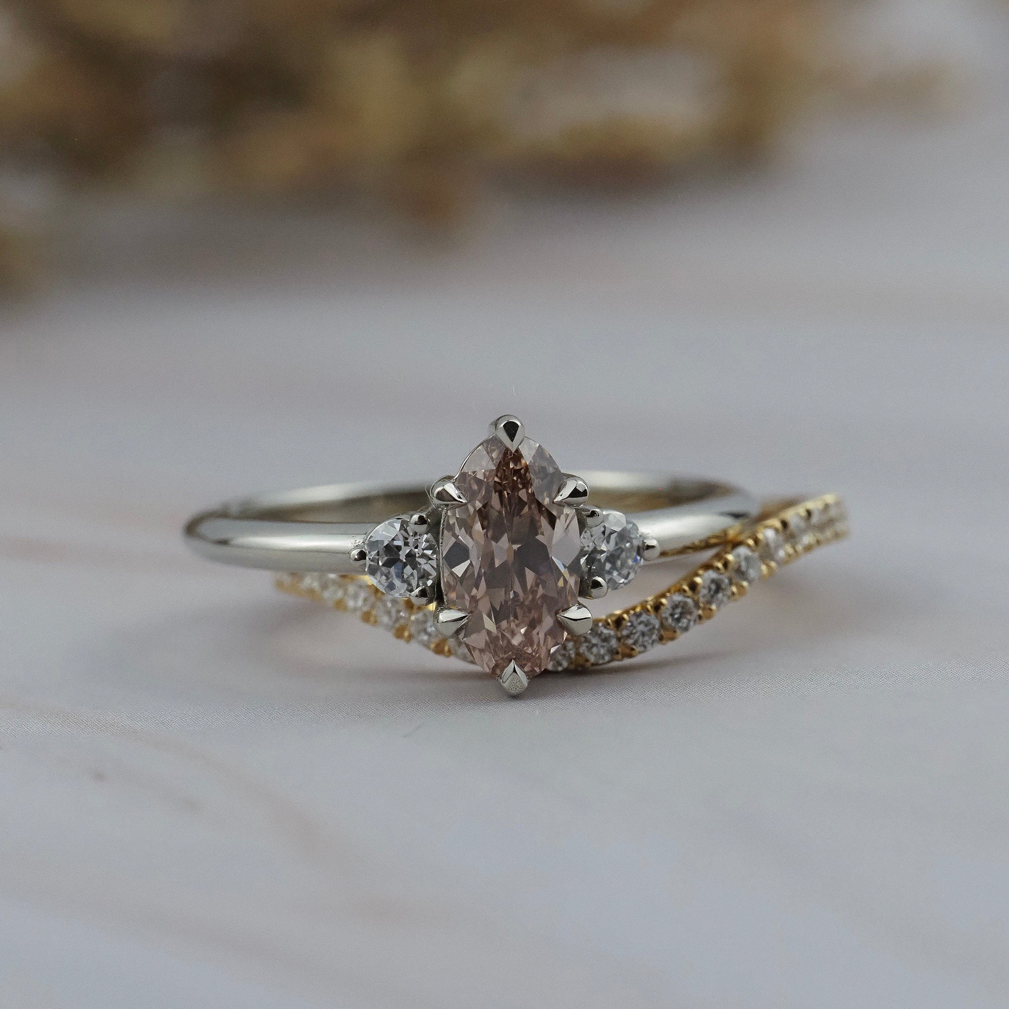Rebecca three stone engagement ring paired with the Pernelle curved diamond pave wedding band, featuring a champagne toned moval cut diamond. 