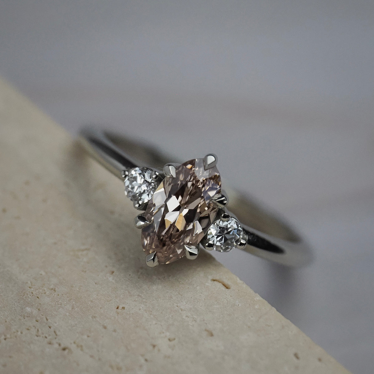 Rebecca three stone engagement ring featuring a champagne  toned moval cut diamond accented by white full cut diamonds.