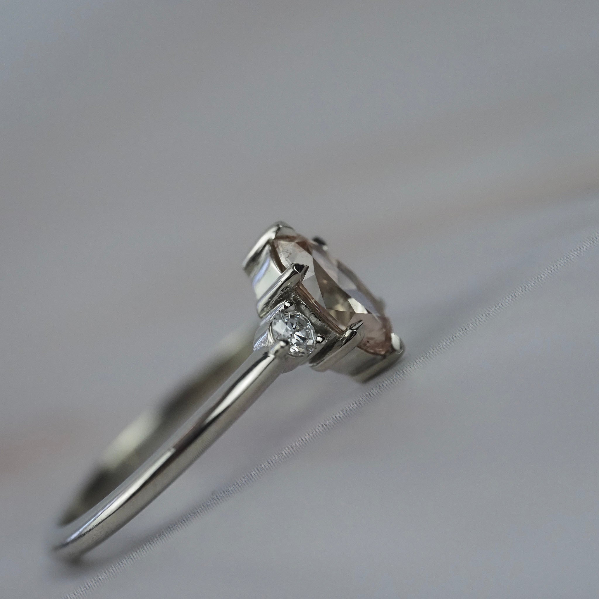 Close-up side profile of the Rebecca three stone engagement ring showing the champagne toned moval cut diamond, white full cuts diamonds, and detailed setting.