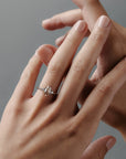 Stylized close-up of the Rebecca three stone engagement ring worn on a a woman's finger, featuring a champagne toned antique cut moval diamond and white full cut diamonds.