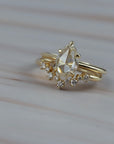 Close-up of the Snowflake curved diamond wedding band paired with a pear-shaped diamond engagement ring. 
