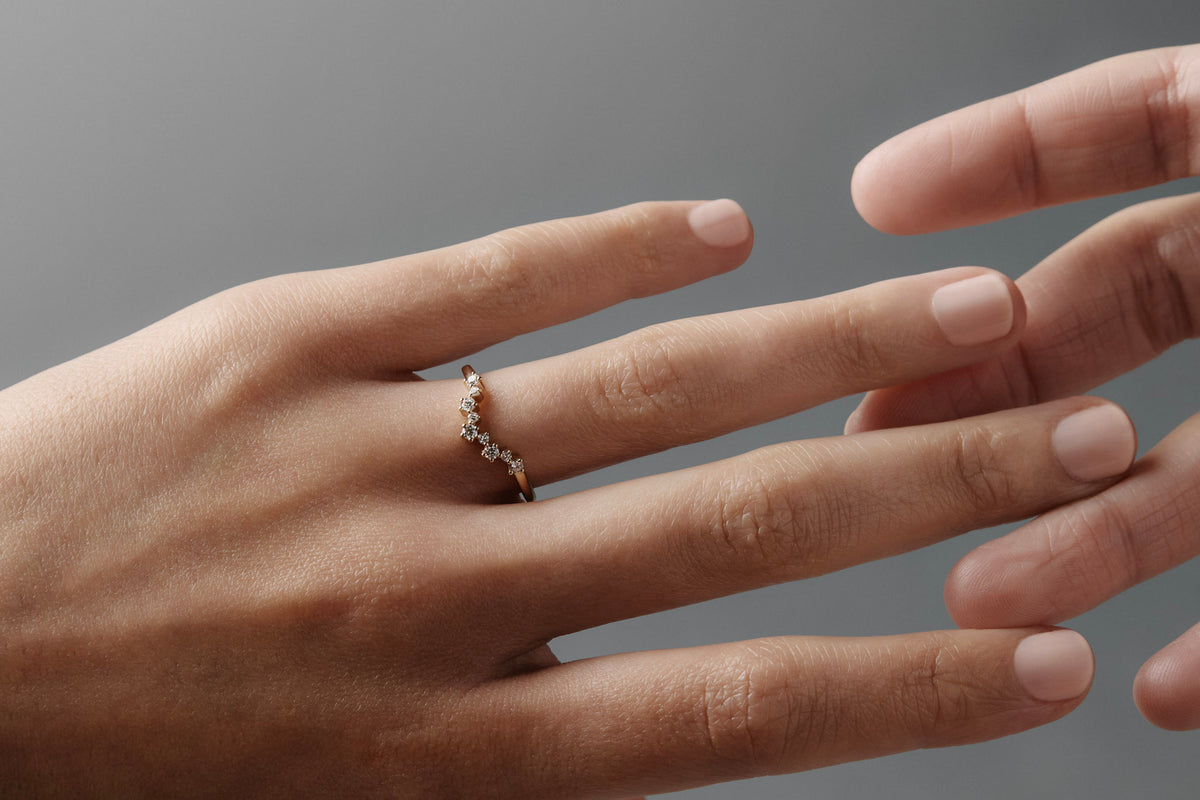 Close-up of a woman wearing the Snowflake curved diamond wedding band on her ring finger. 