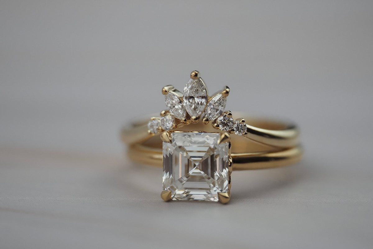 Trillium curved gold wedding band paired with an asscher-cut diamond engagement ring.