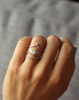 Close up of model hand wearing the curved flow womens wedding band by Fluid Jewellery in rose gold